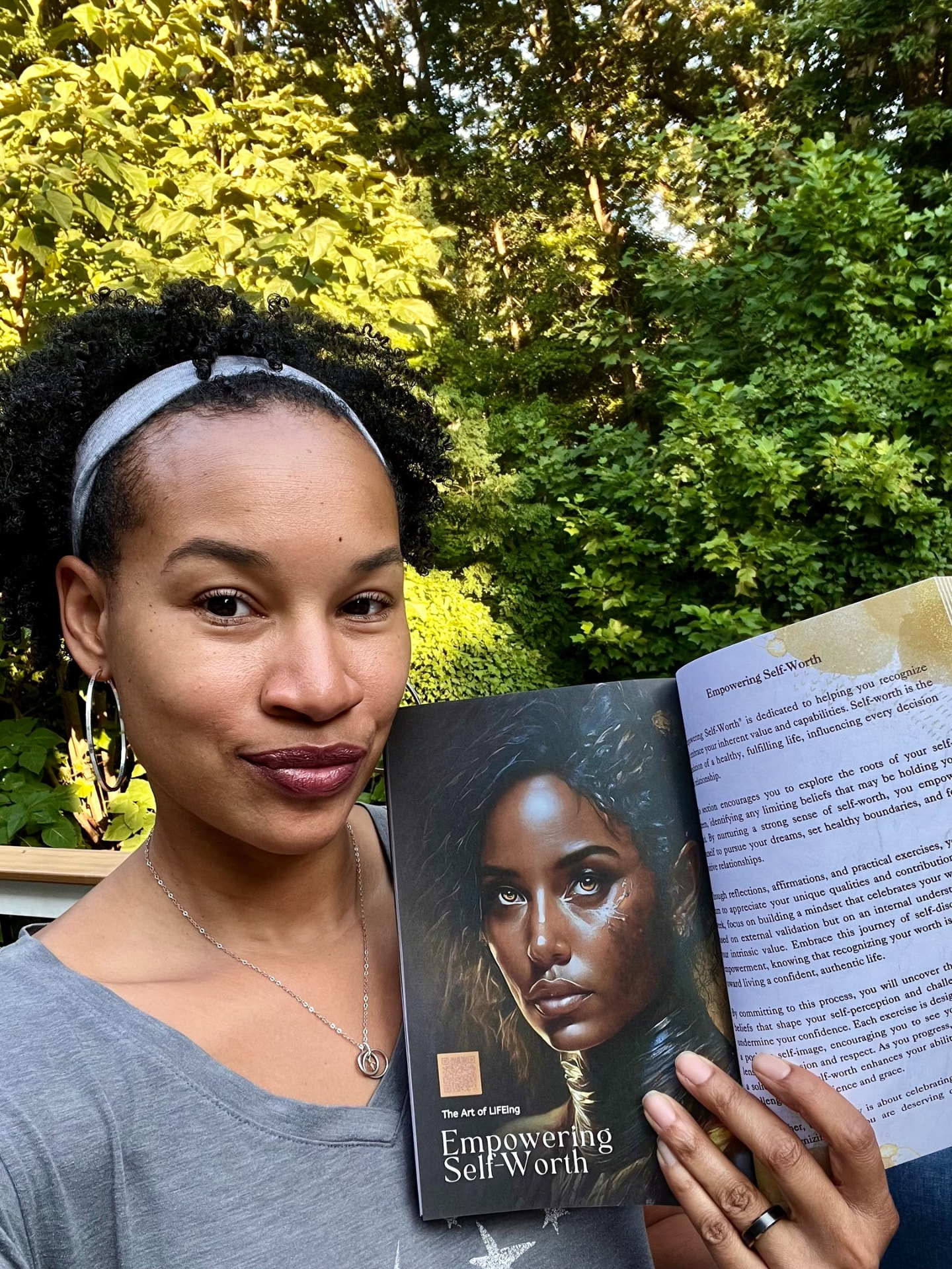 Reader outdoors holding The Art of LIFEing Journal open to the Empowering Self-Worth chapter
