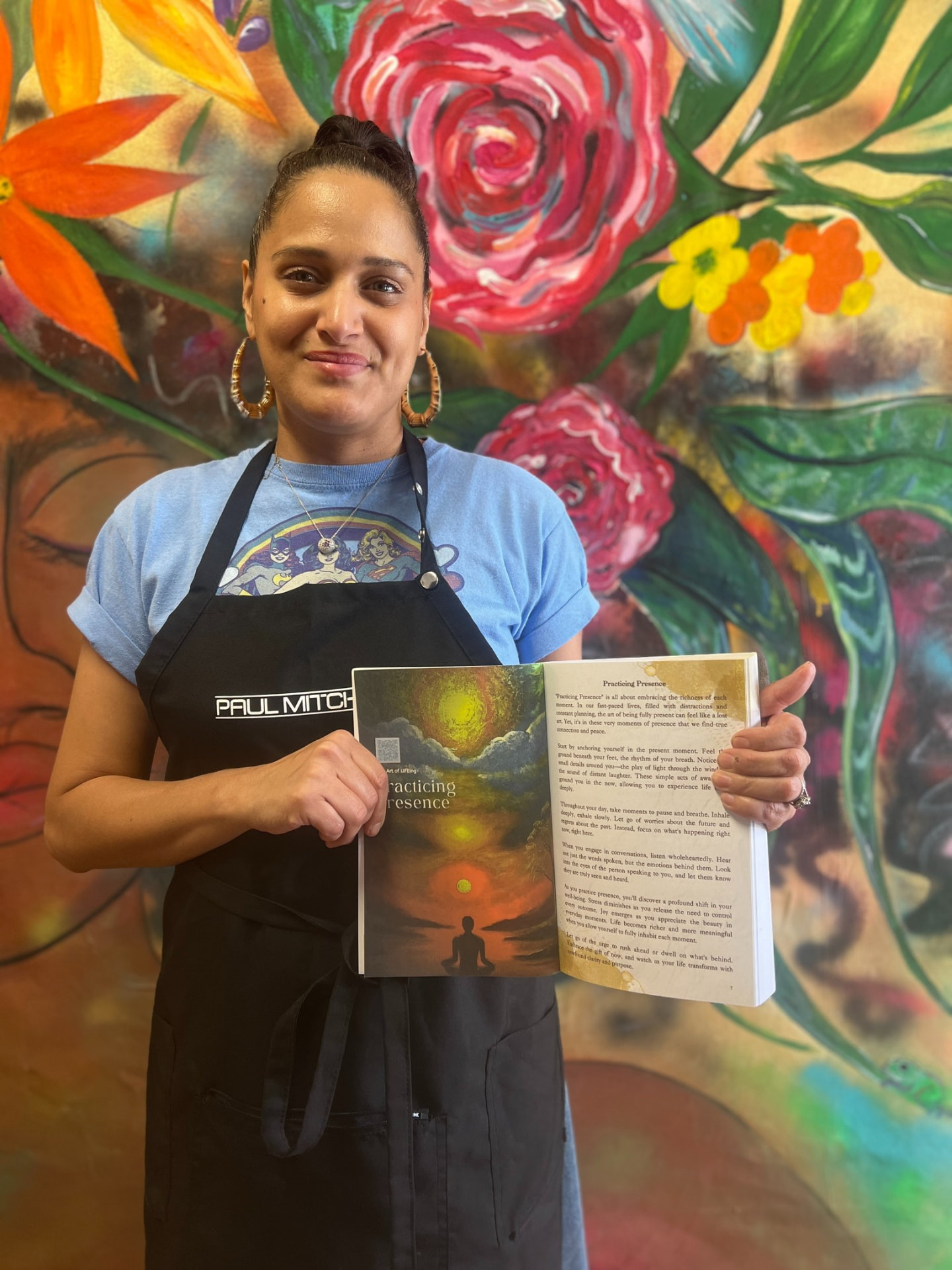 Reader in a salon apron holding The Art of LIFEing Journal open to the Practicing Presence chapter