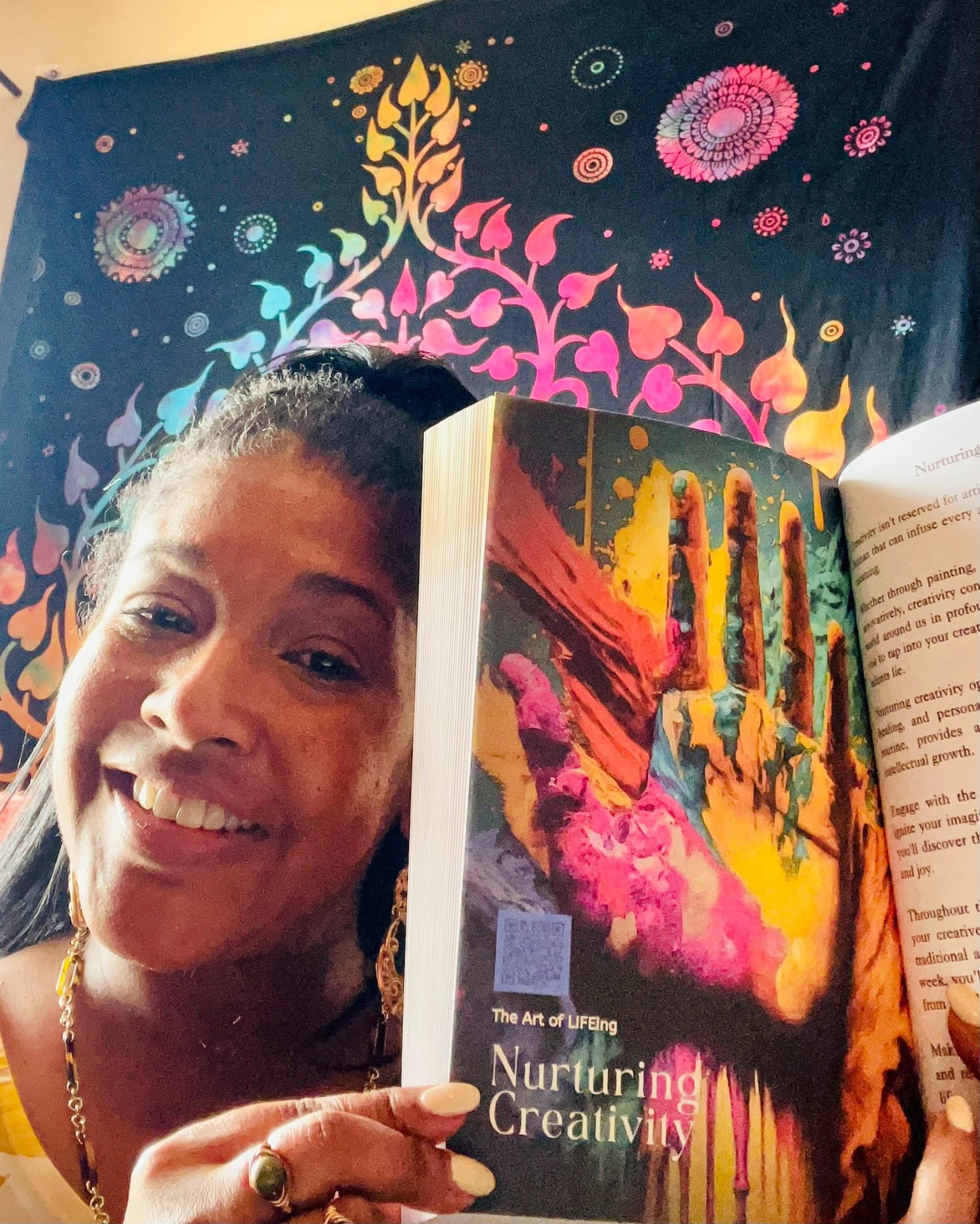 Reader smiling beside The Art of LIFEing Journal open to the Nurturing Creativity chapter